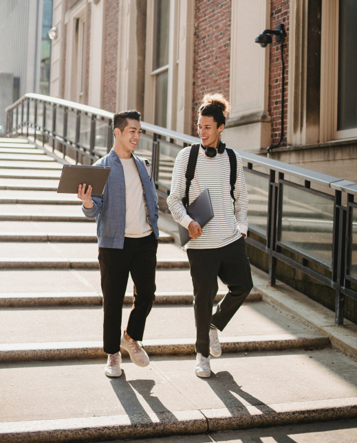 deux jeunes étudiants avec un ordinateur portable en mains descandants des escaliers